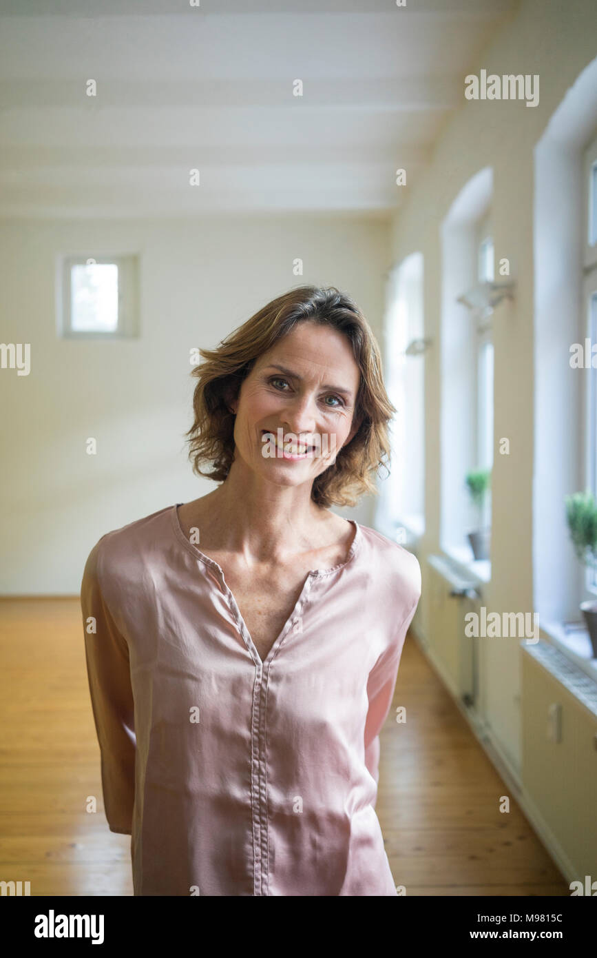 Portrait of smiling mature woman in empty room Stock Photo - Alamy