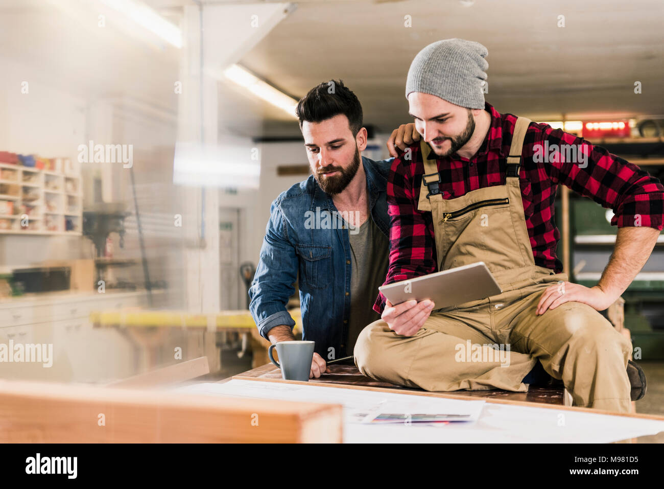 Two men with tablet looking at draft in workshop Stock Photo