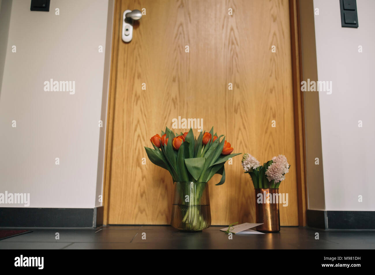 Farewell flowers, candle and condolende card at apartment door of deceased neighbour Stock Photo