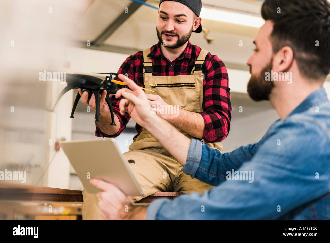 Two men discussing about drone in workshop Stock Photo