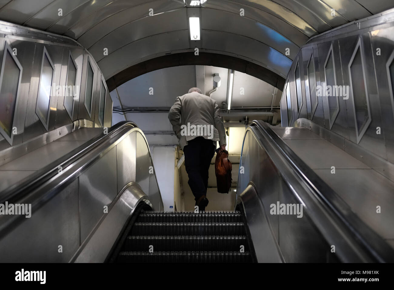 Man stepping off escalator on London Underground Stock Photo