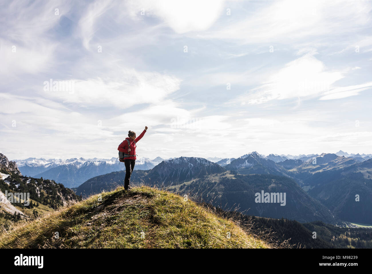 Austria, Tyrol, young woman standing in mountainscape cheering Stock Photo