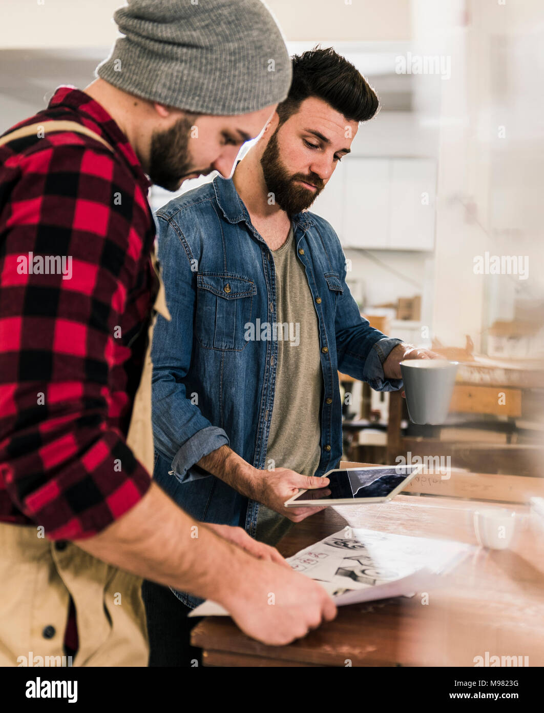 Two men with tablet looking at draft in workshop Stock Photo