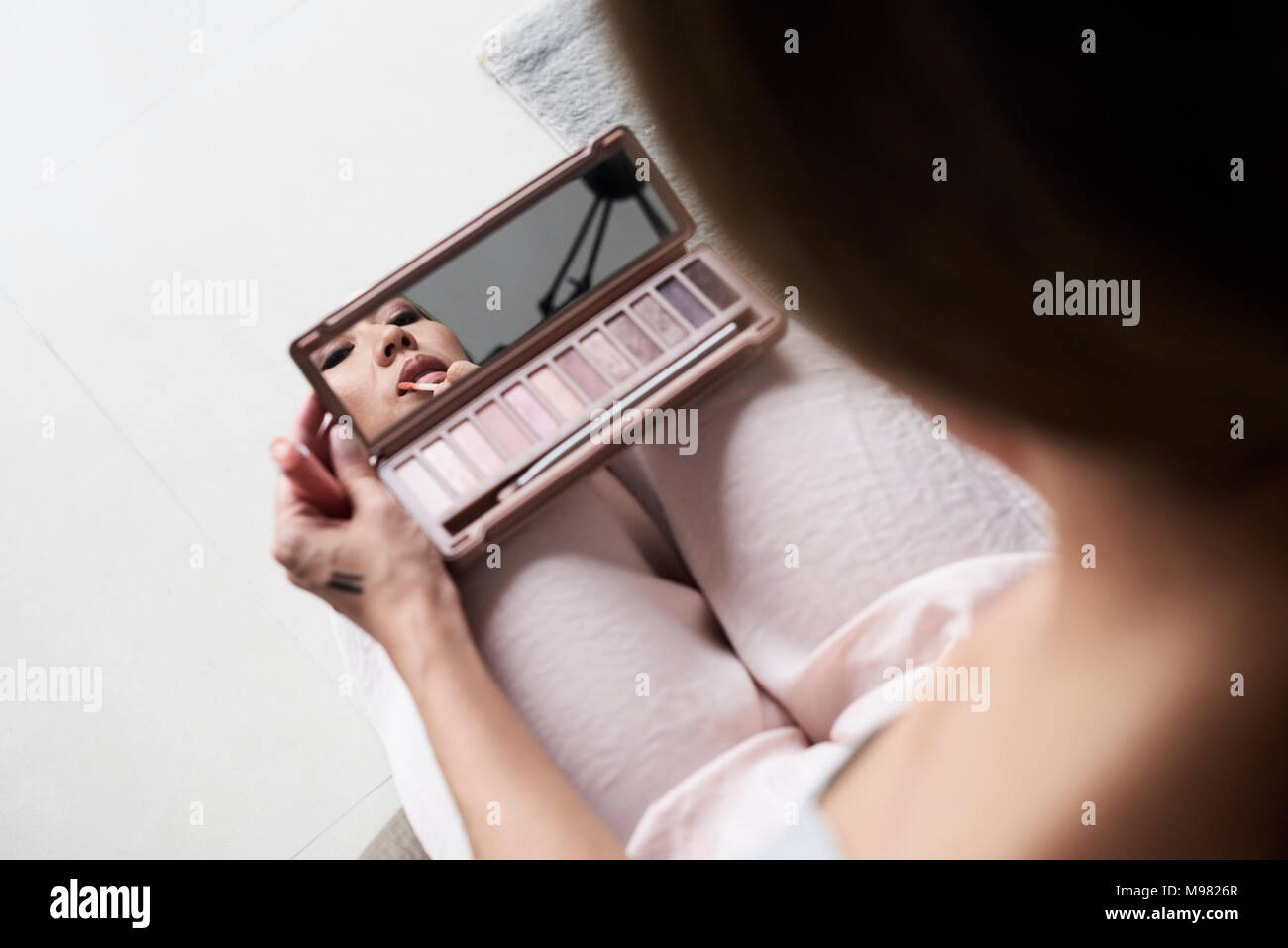 Woman using hand mirror applying lipstick Stock Photo