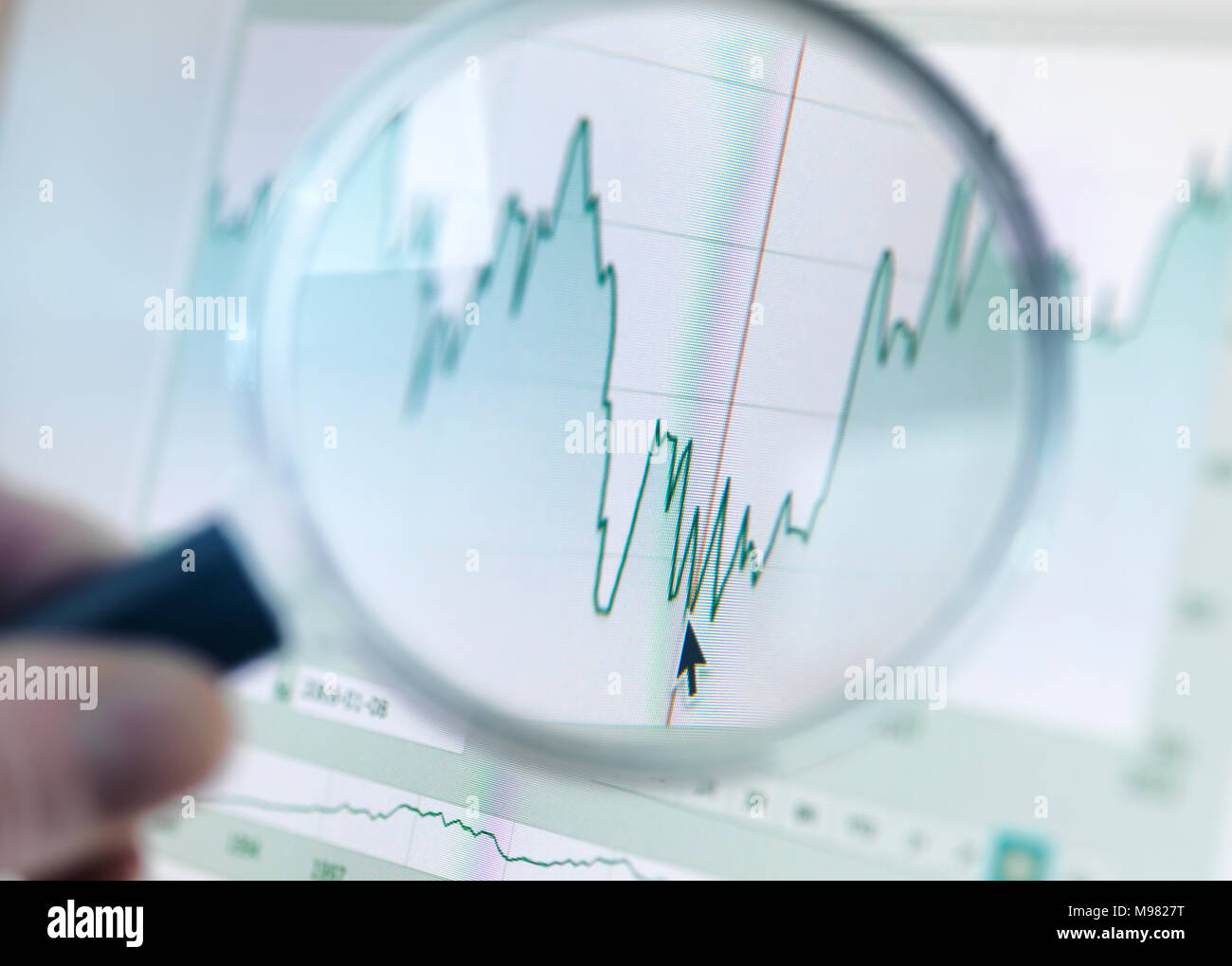Investor analysing line graph on computer screen with magnifying glass Stock Photo