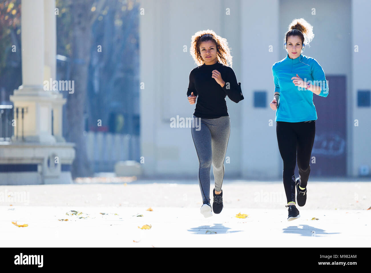Two focused young women running listening to music Stock Photo