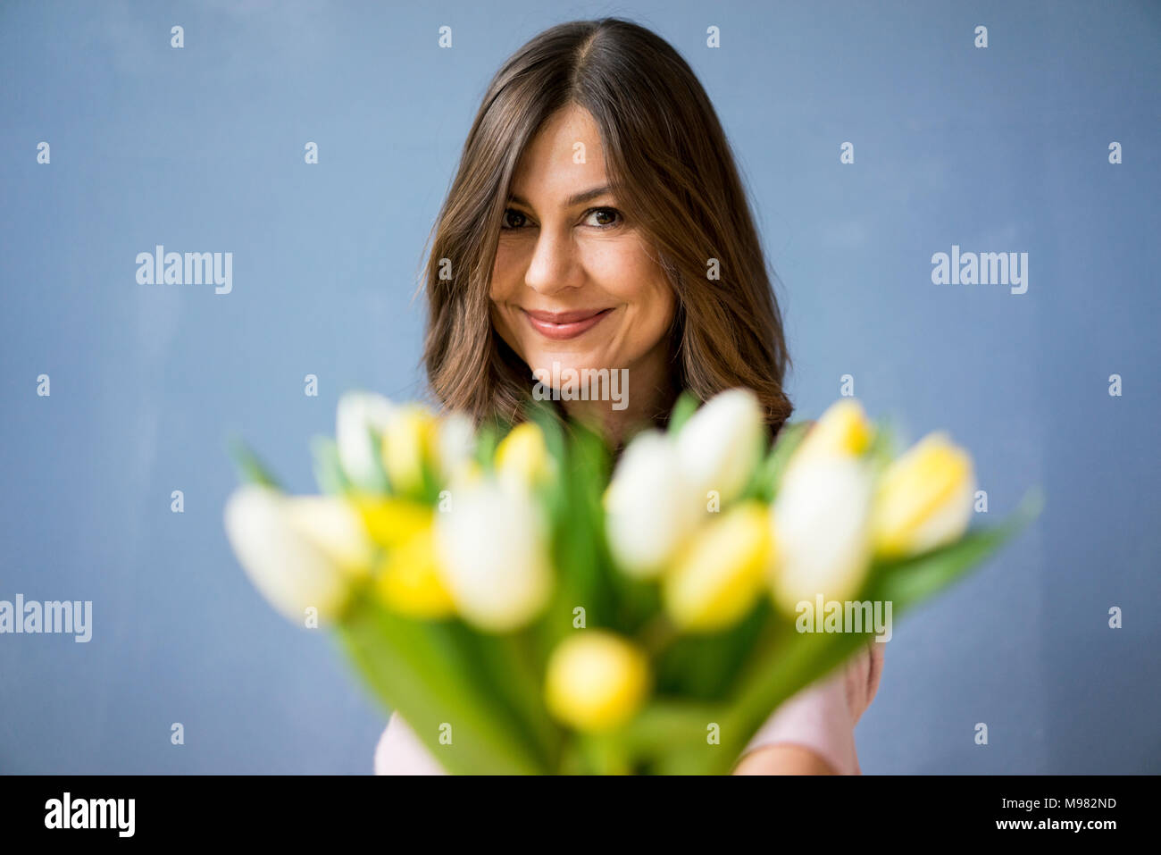 Portrait of smiling woman holding bunch of tulips Stock Photo