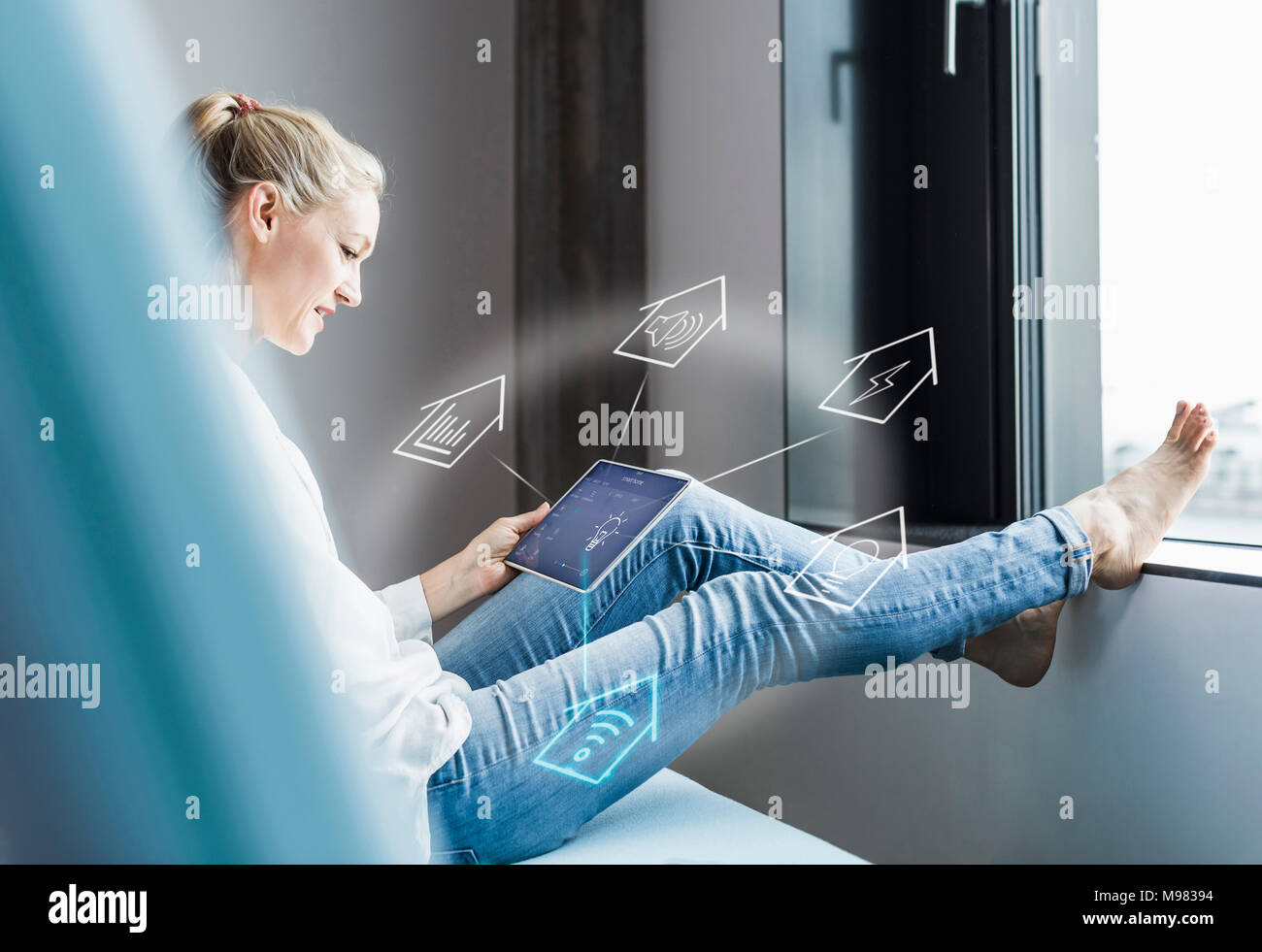 Woman sitting in office, using digital tablet to remote-control his smart home Stock Photo