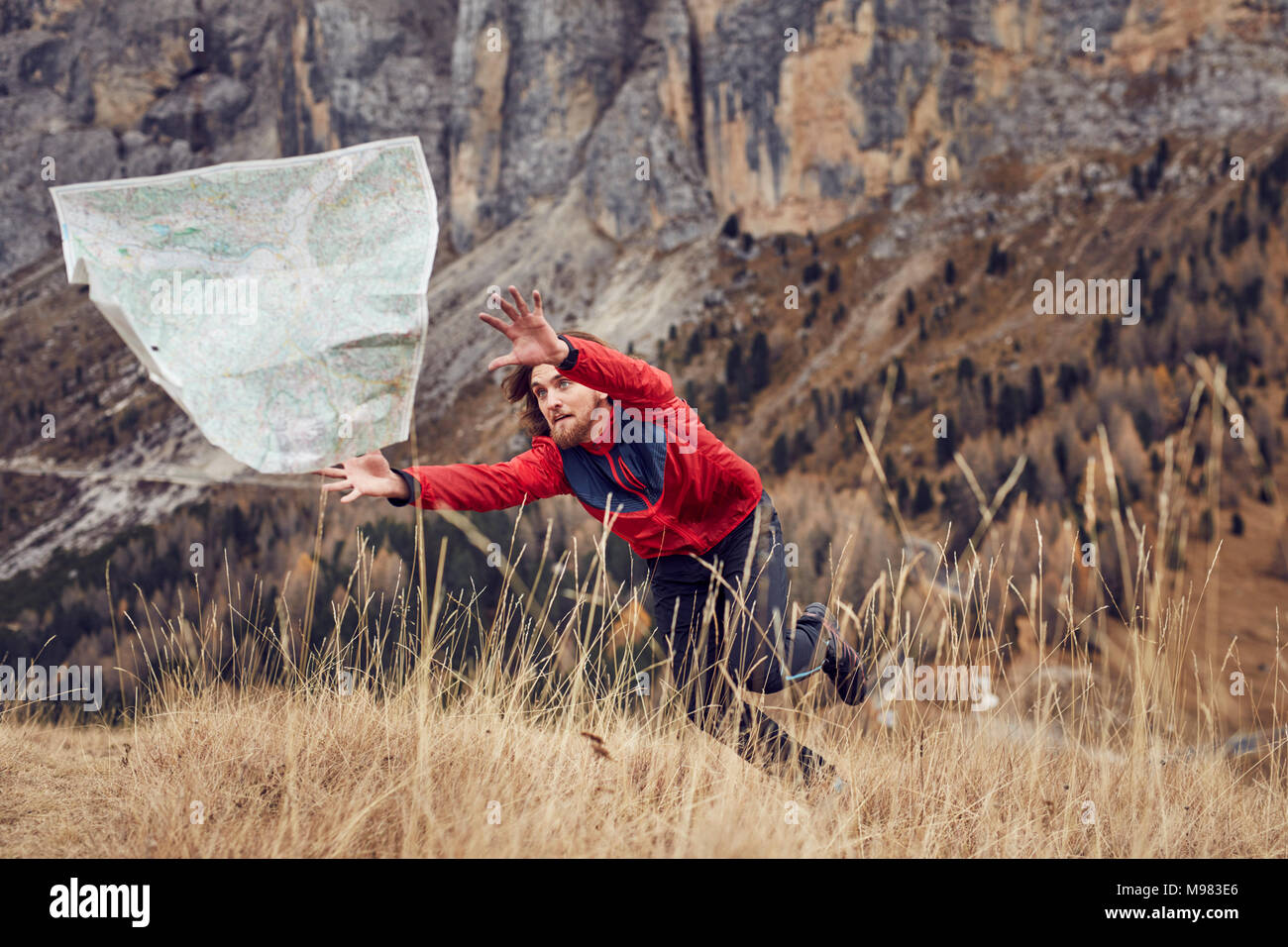 Mountain hiker chasing map flying away Stock Photo