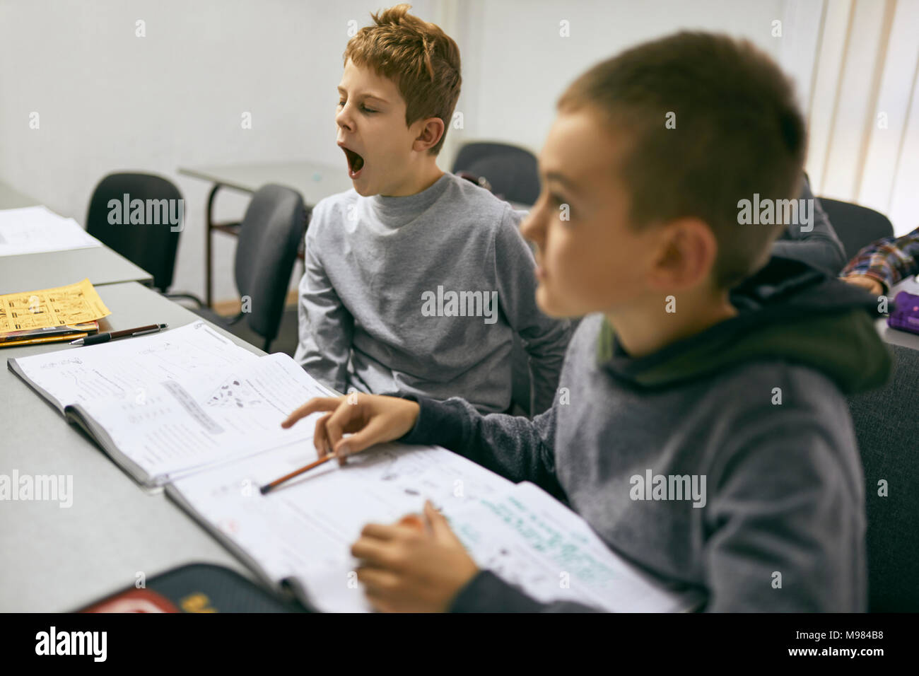 Students learning in class with boy yawning Stock Photo