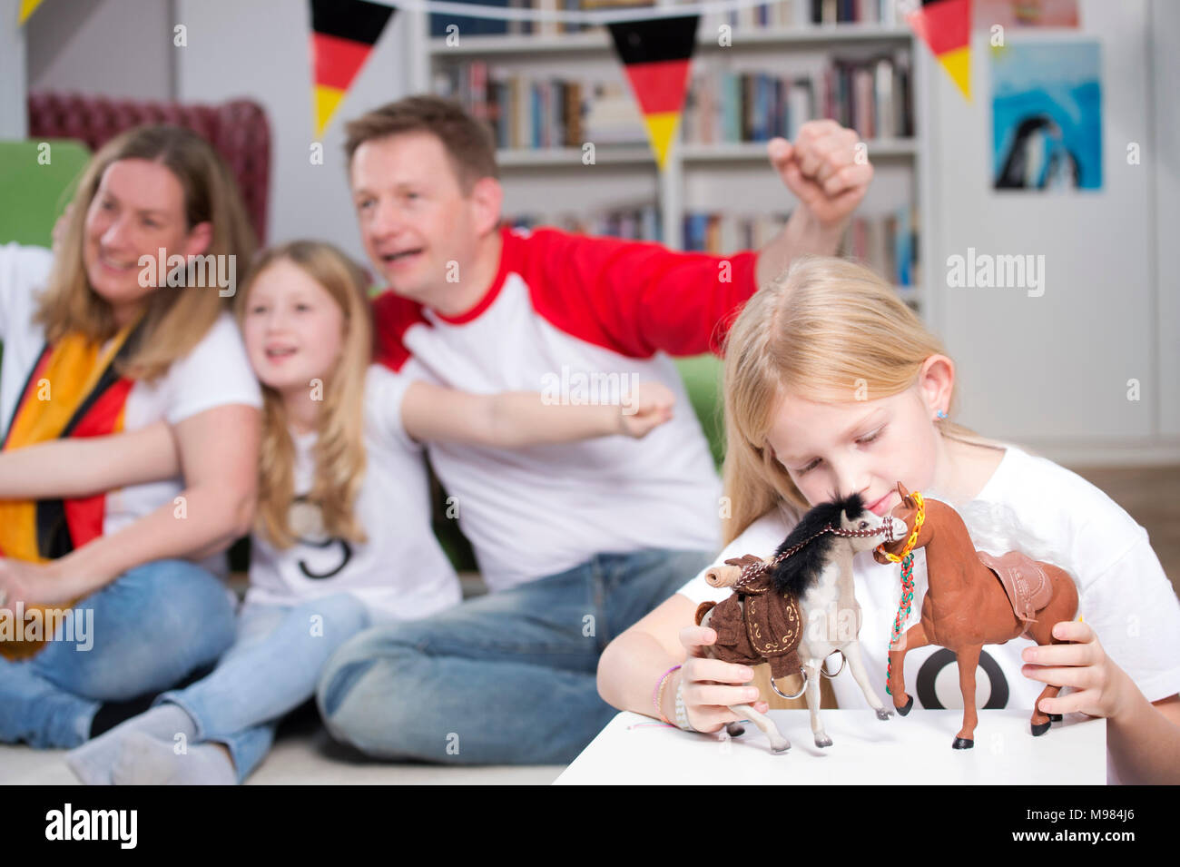 Family watching football world cup on TV, while little girl is playing with toys Stock Photo