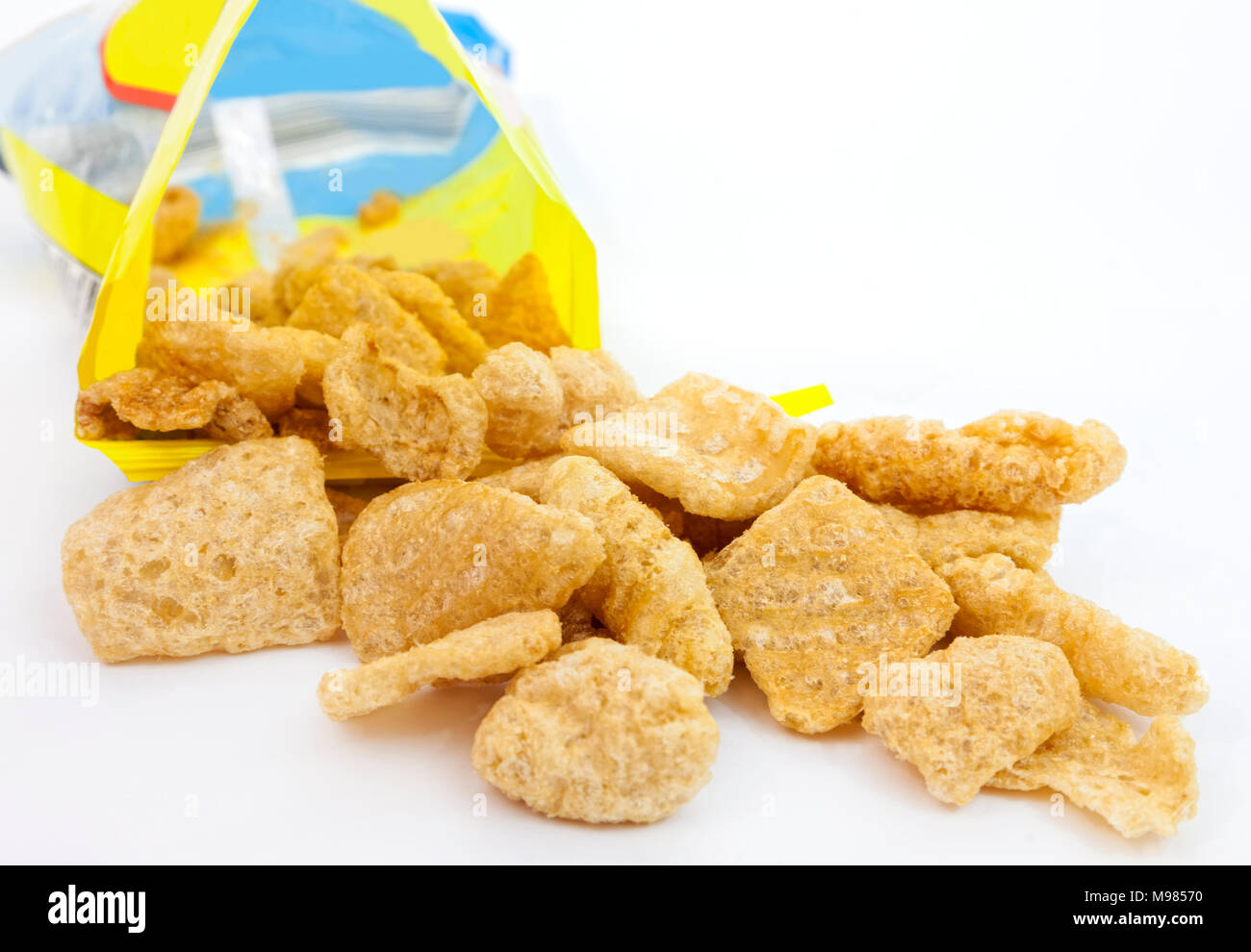 Pork rinds or chicharones spilling from open snack bag. Shallow DOF. Stock Photo