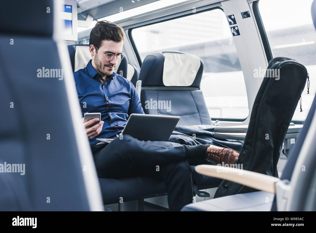 Businessman working in train using laptop Stock Photo Alamy