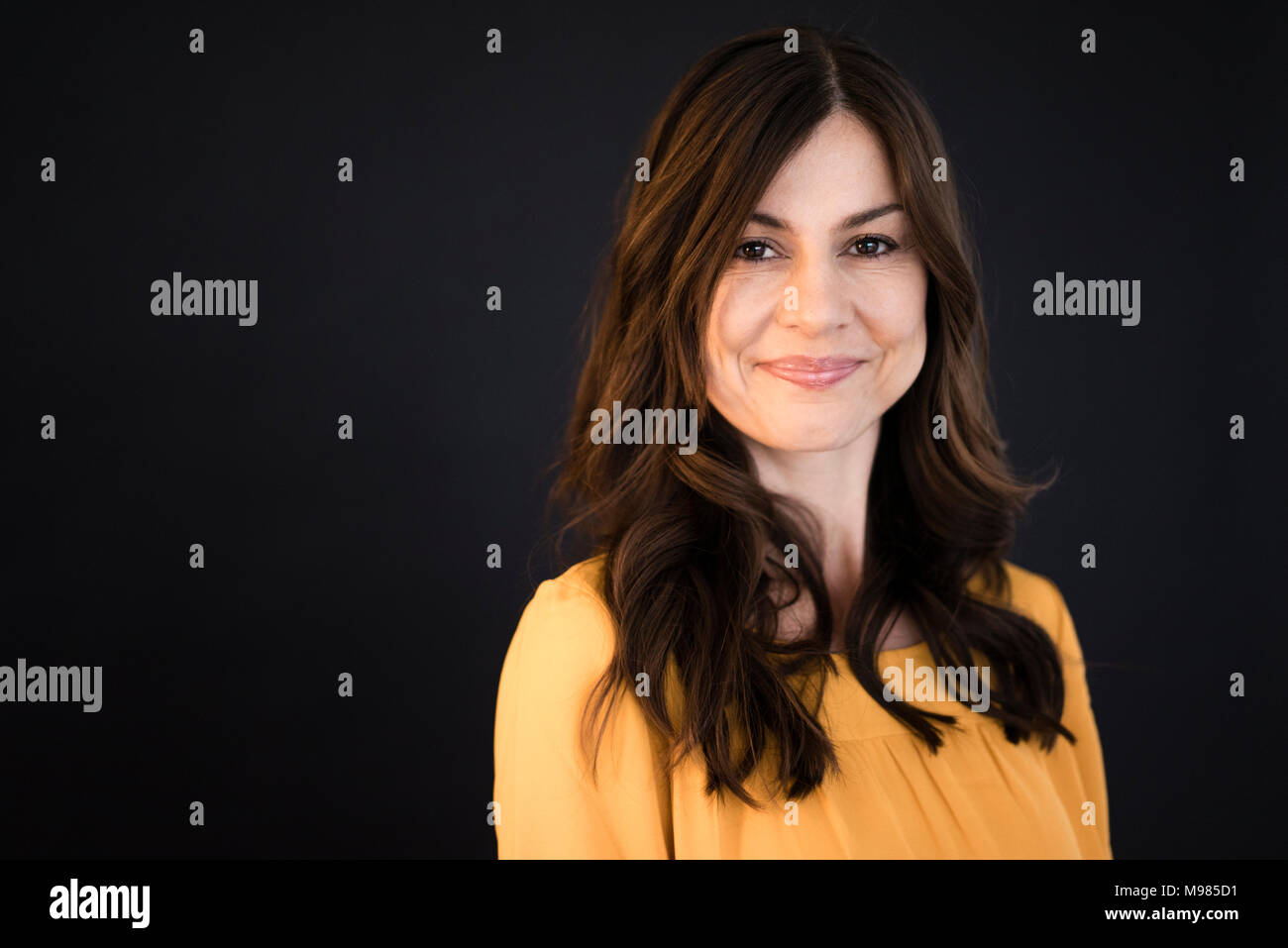 Portrait of smiling woman in front of black wall Stock Photo - Alamy
