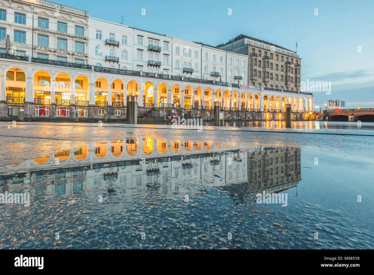 Germany, Hamburg, Kleine Alster with Alsterarkaden in the evening, mirrored in puddle Stock Photo