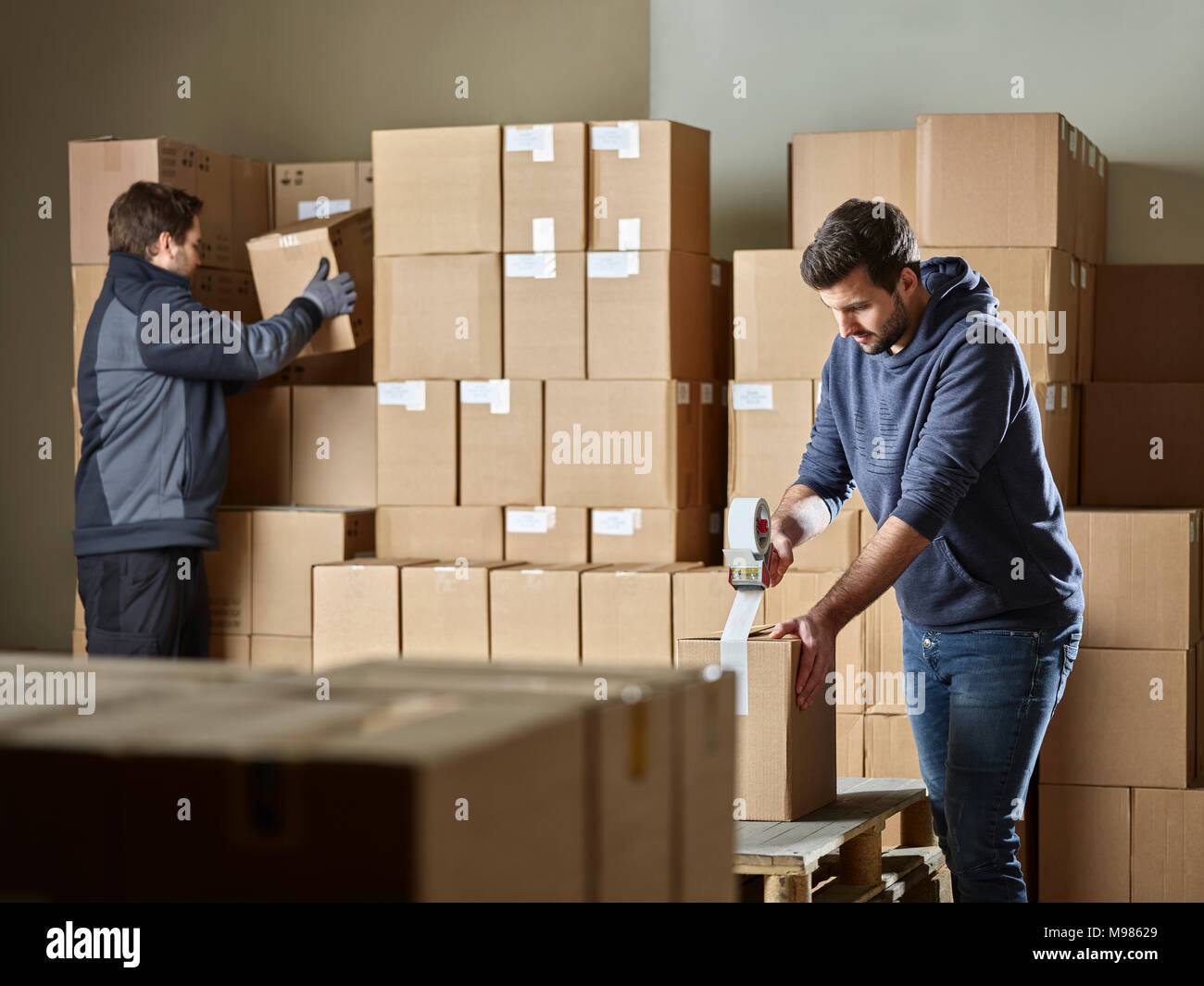 Workers closing packages with package tape Stock Photo