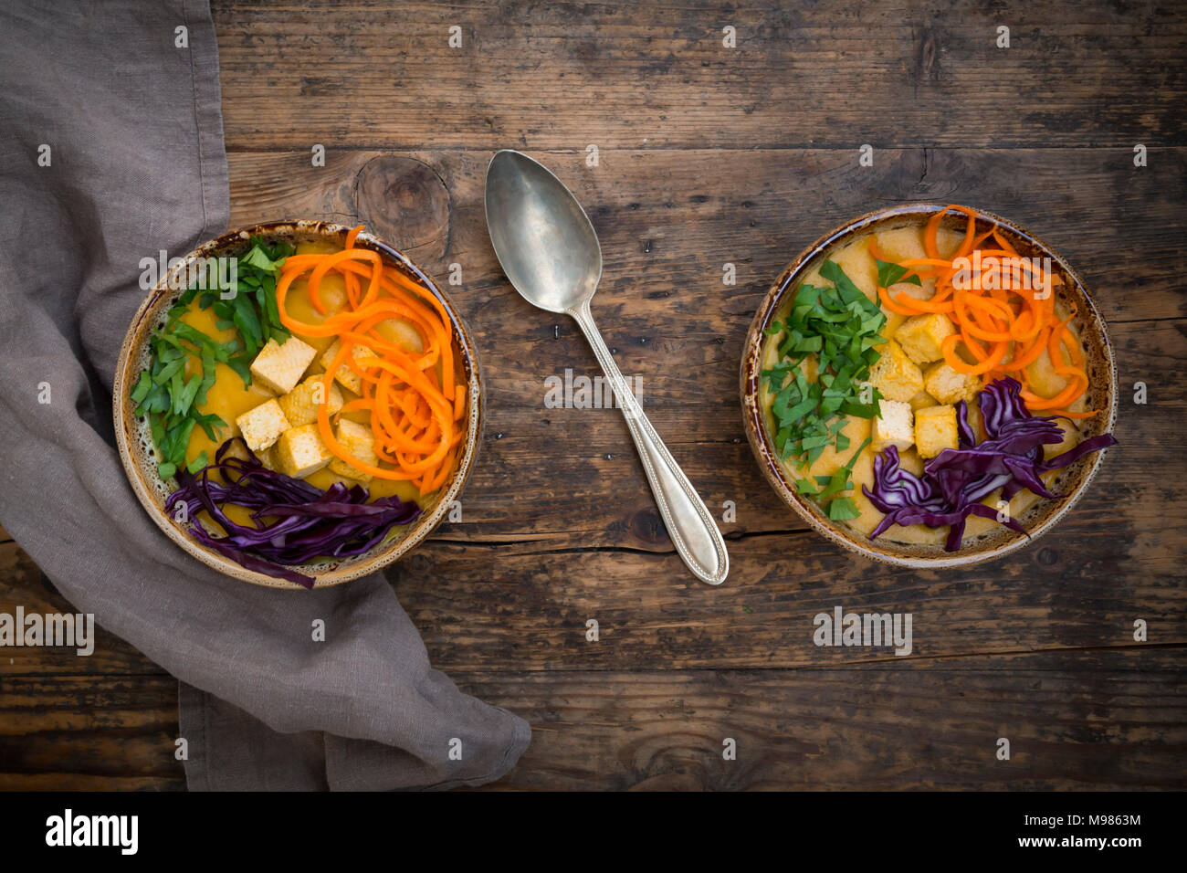 Turmeric curry dish with carrot, tofu, red cabbage and parsley in bowl Stock Photo