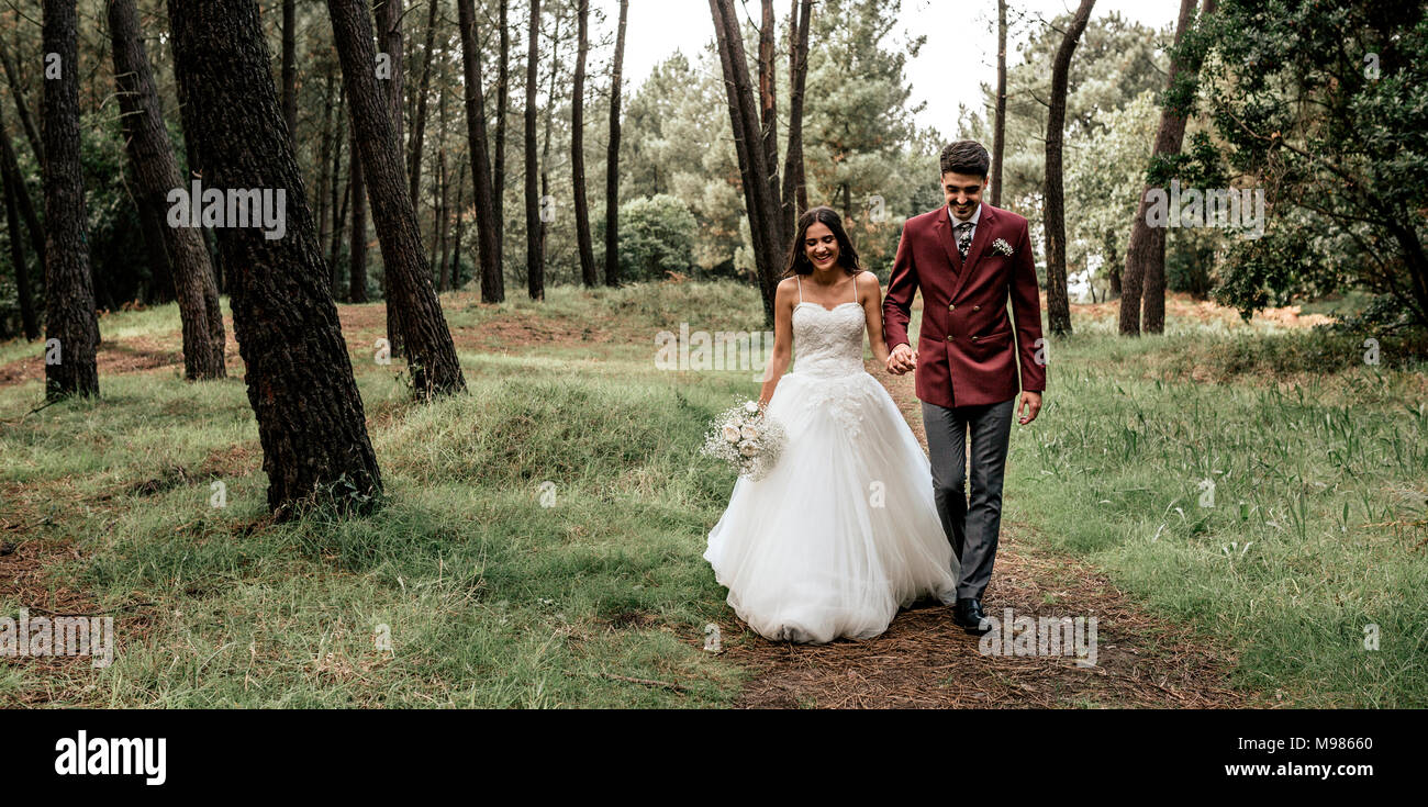 Happy bride and groom walking in forest Stock Photo - Alamy