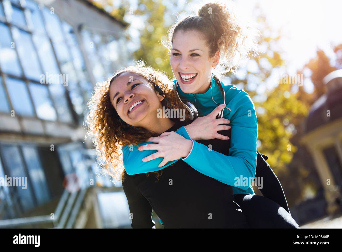 Happy young woman carrying friend piggyback Stock Photo