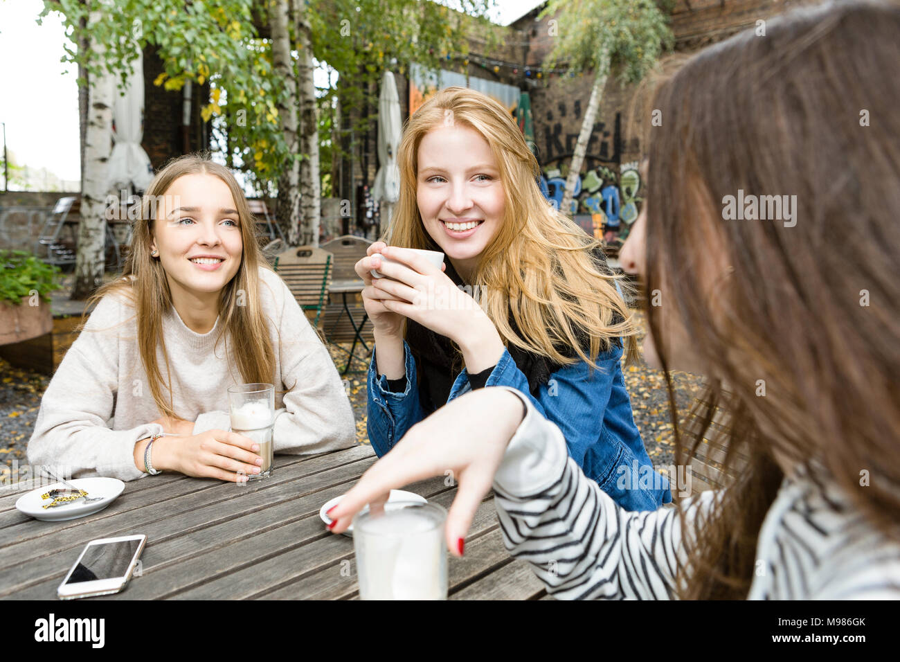 Germany, Berlin, group of three friends drinking coffee in sidewalk cafe Stock Photo