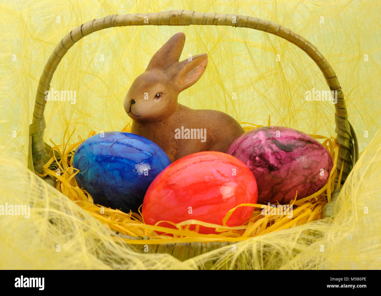 bunny and three painted eggs in easter nest Stock Photo