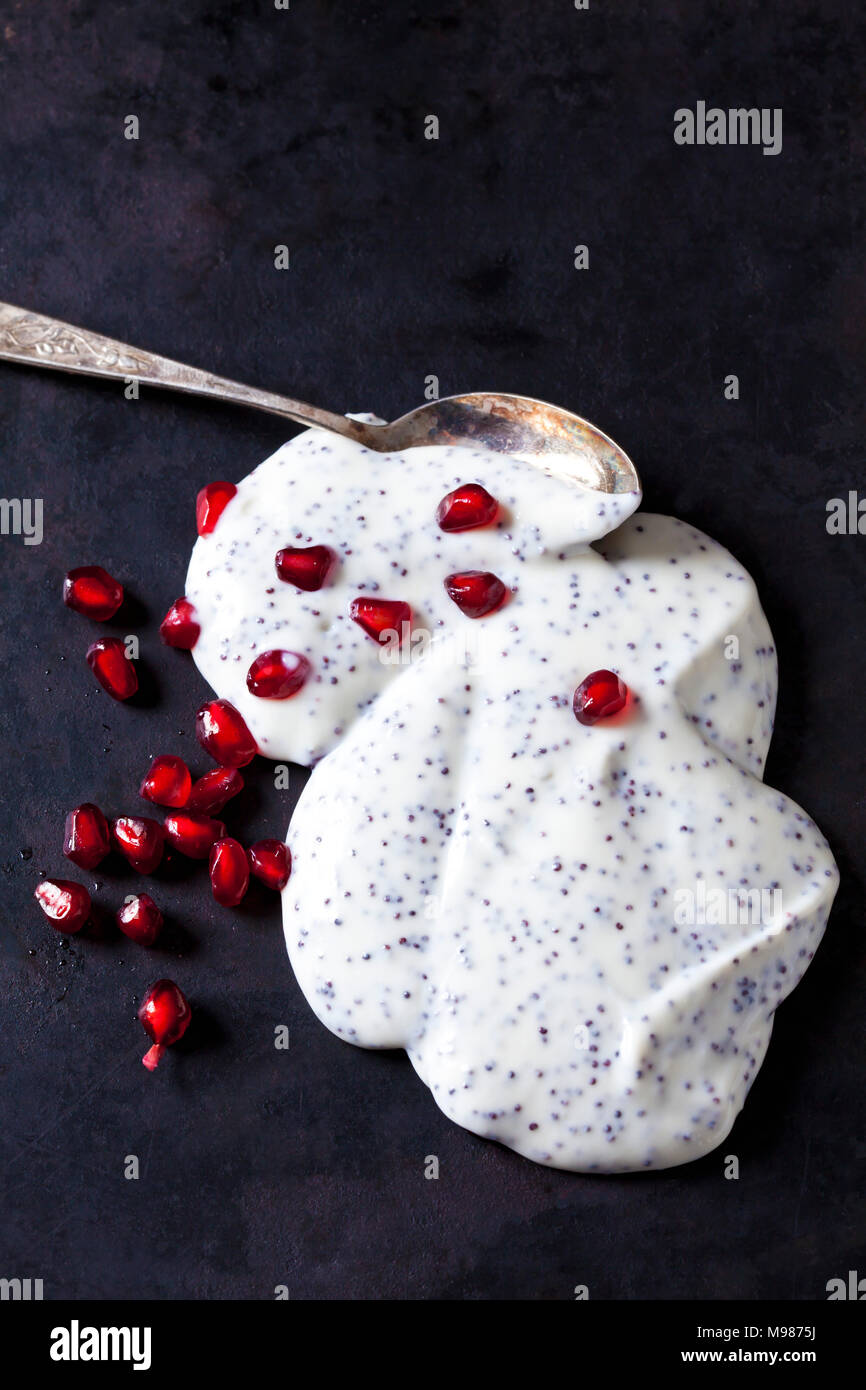 Natural yoghurt with poppy seed and pomegranate seed on dark ground Stock Photo