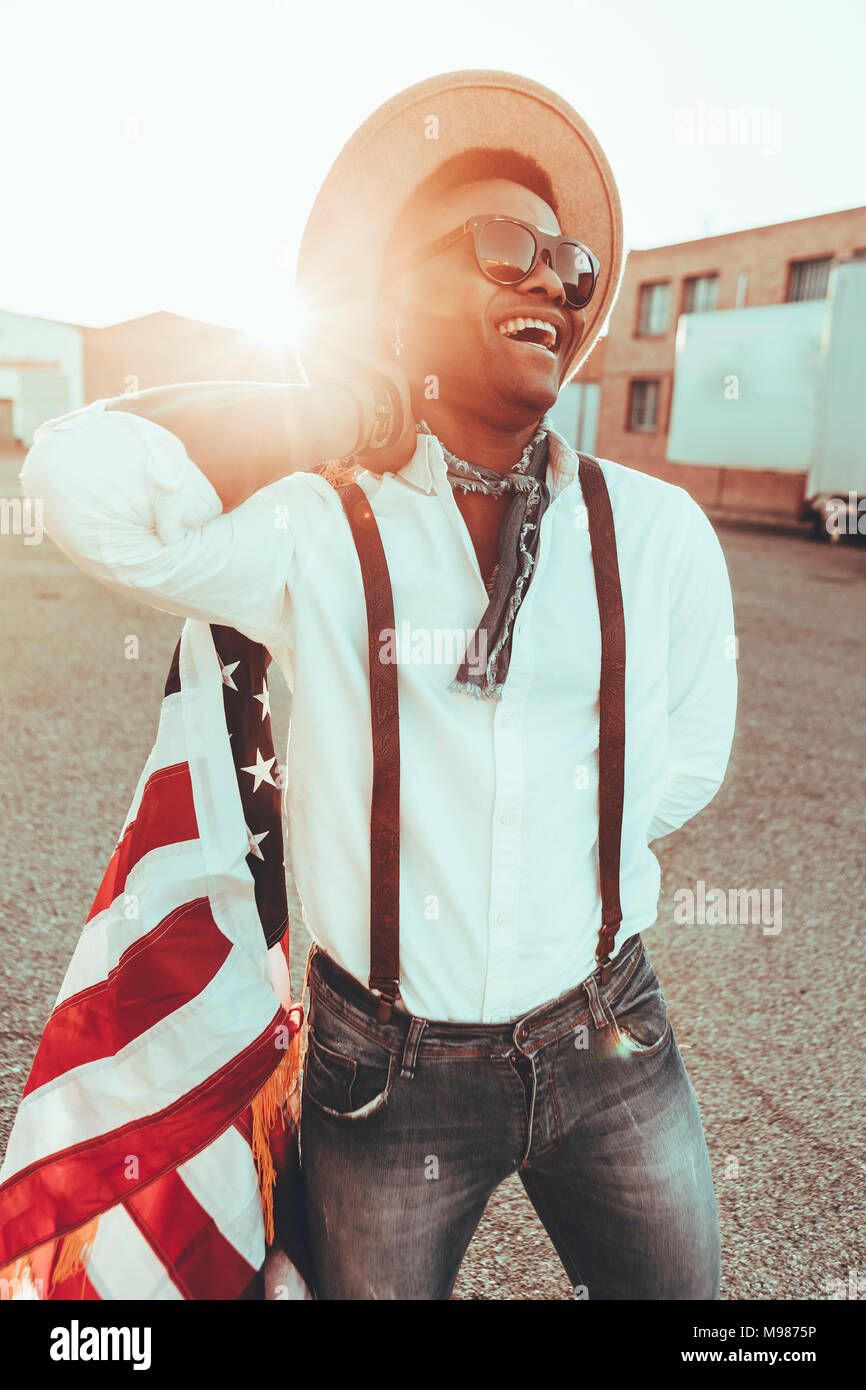 Portrait of laughing young man with American flag at backlight Stock Photo