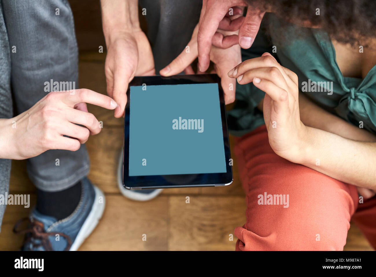 Four people sharing tablet Stock Photo