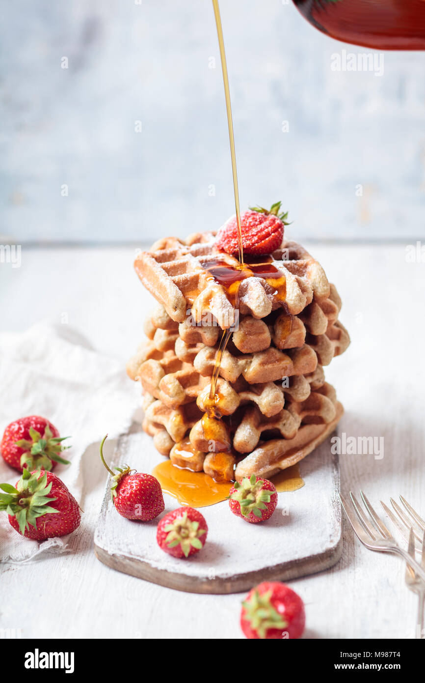 Belgian waffles with strawberries and powdered sugar, maple sirup Stock Photo