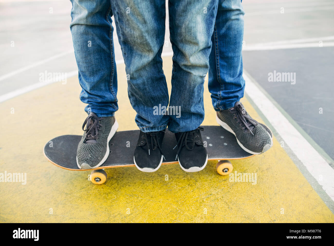 Legs of adult and child on skateboard Stock Photo