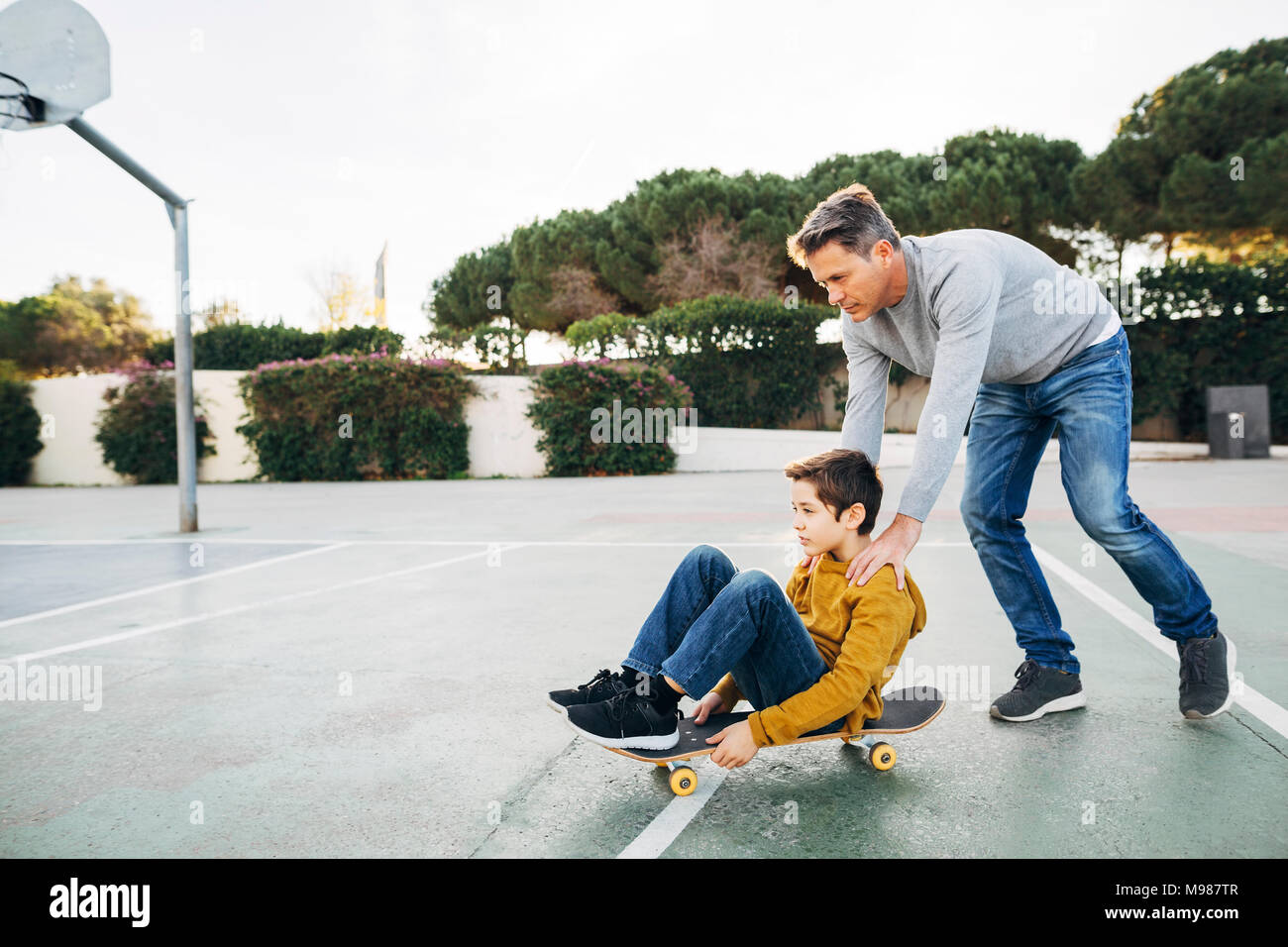 Father assisting son riding skateboard Stock Photo