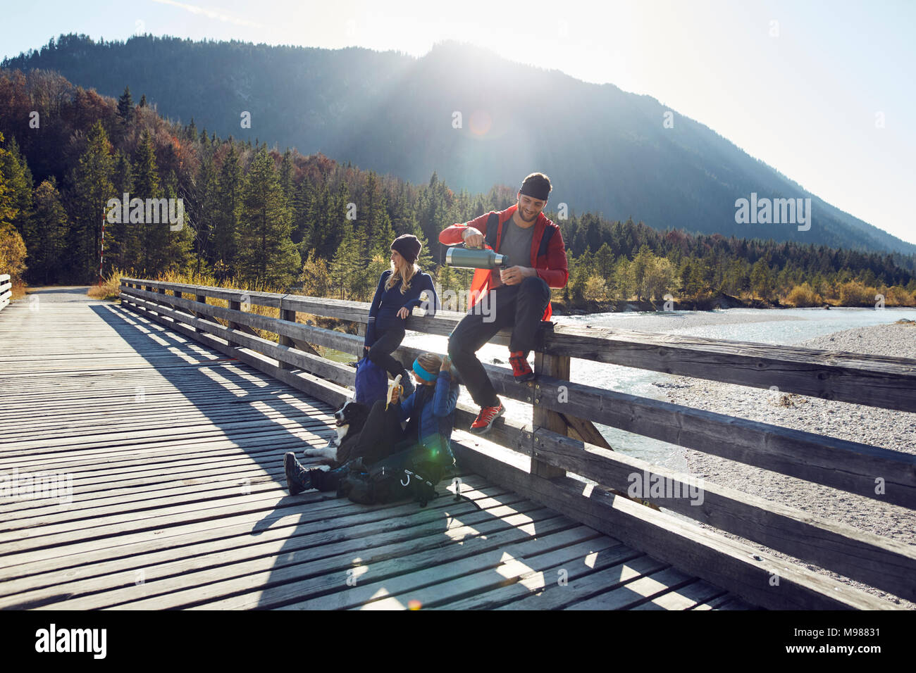 Group of friends with dog hiking resting on a bridge Stock Photo