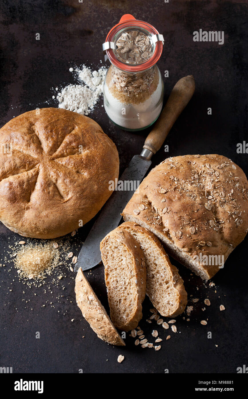 Two spelt breads and glass bottle of ingredients for preparing spelt bread Stock Photo