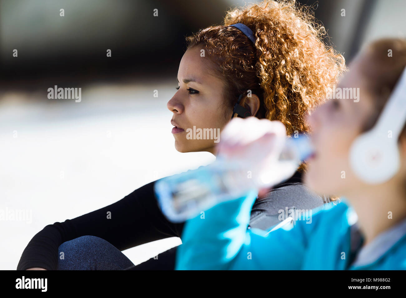Two sportive young women having a break listening to music Stock Photo