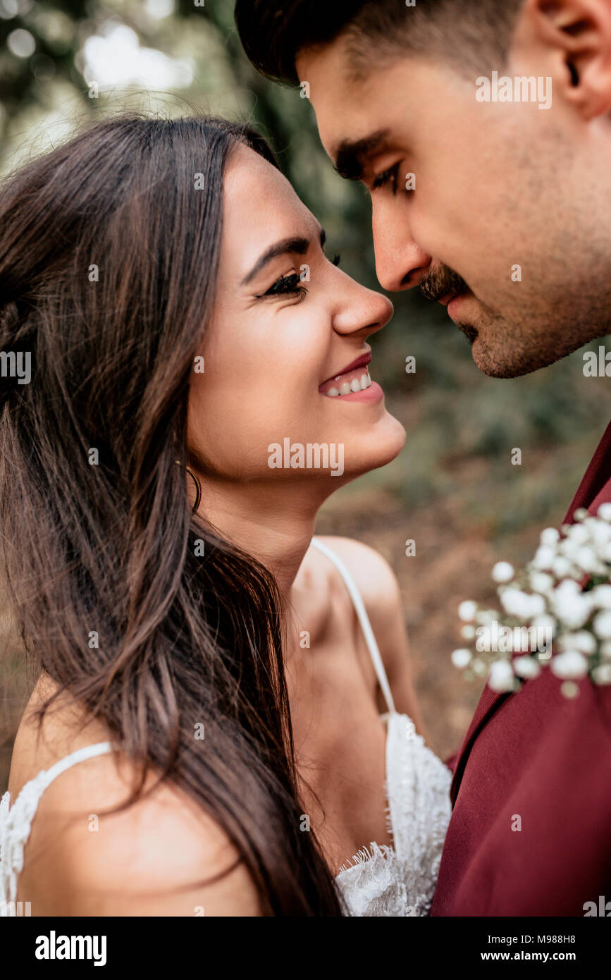 Portrait of happy and smiling bride looking at man with moustache outdoors Stock Photo