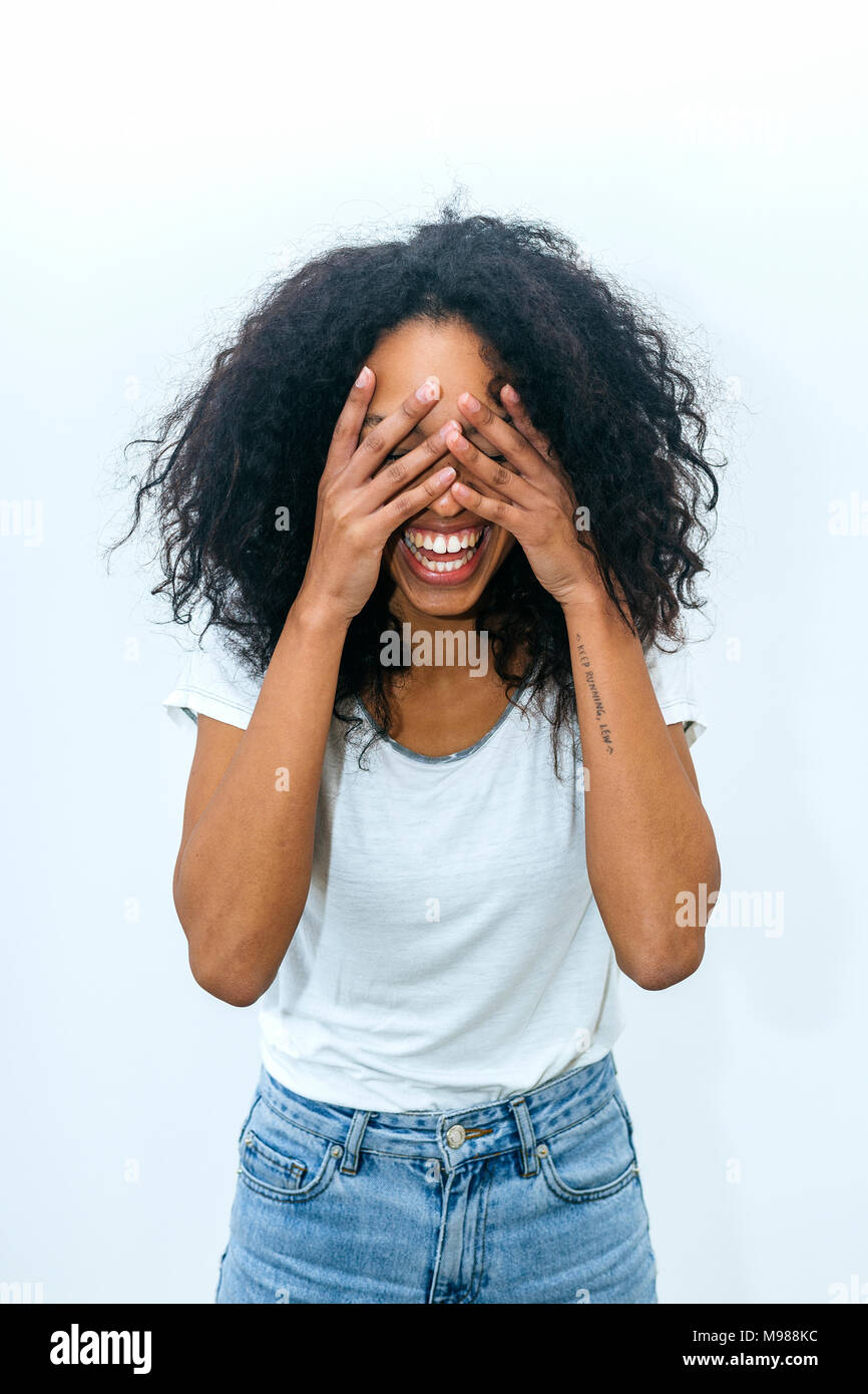 Portrait of laughing young woman covering eyes with her hands Stock