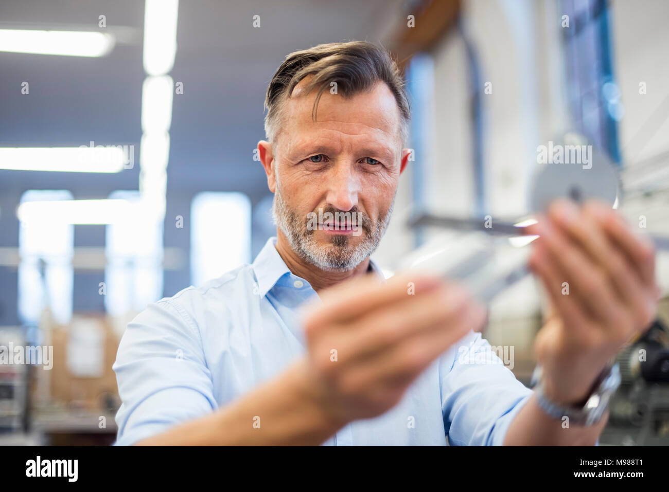Mature businessman in factory examining component Stock Photo