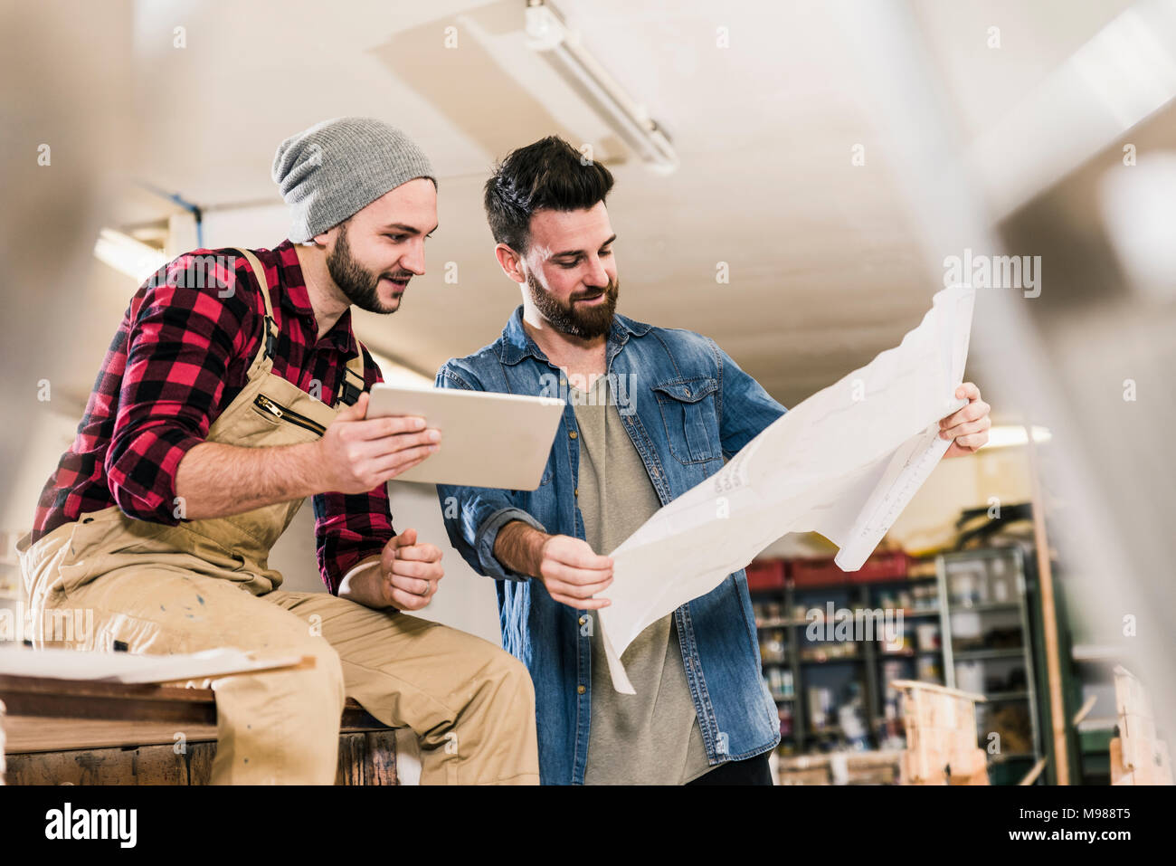 Two men with tablet looking at draft in workshop Stock Photo
