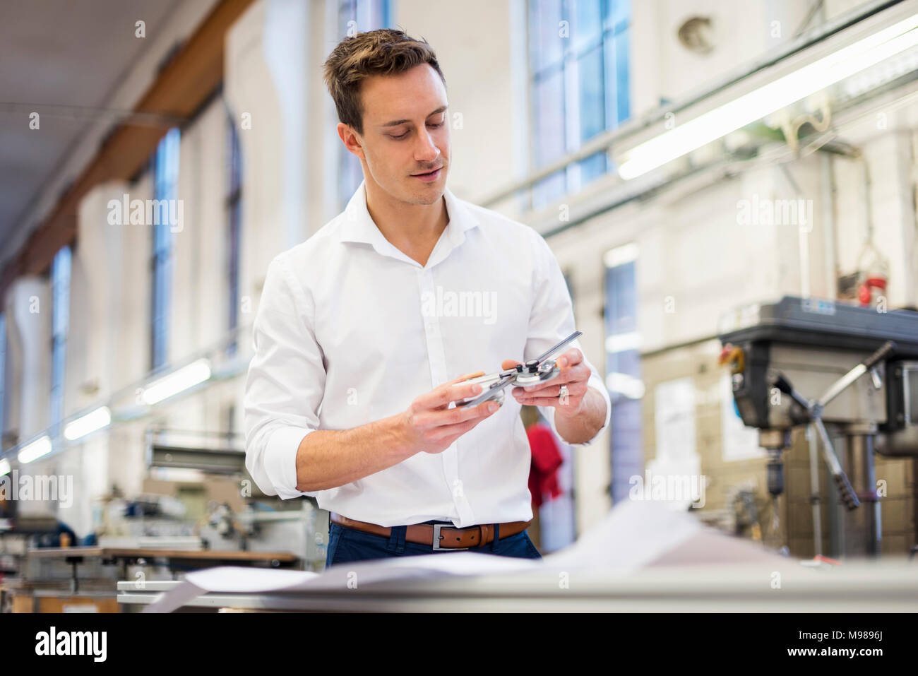 Young businessman in factory holding component Stock Photo