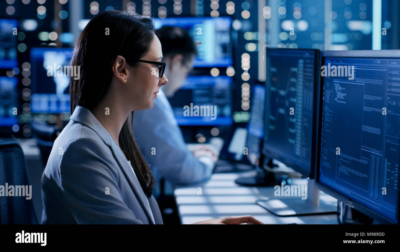 Female Engineer Controller Observes Working of the System. In the Background People Working and Monitors Show Various Information. Stock Photo