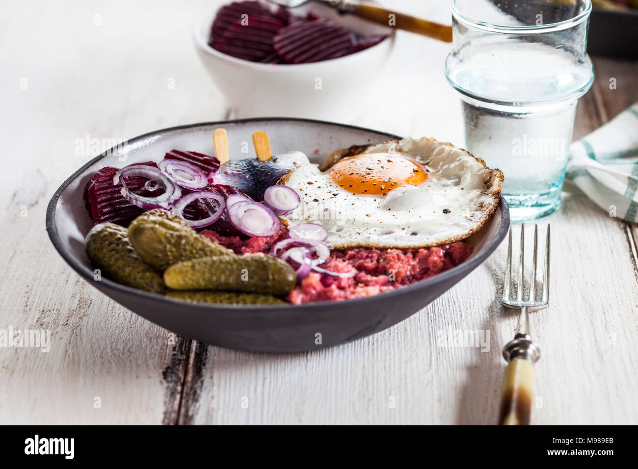 Labskaus, rollmops, pickled gherkin, beetroot salad, onion and fried egg Stock Photo