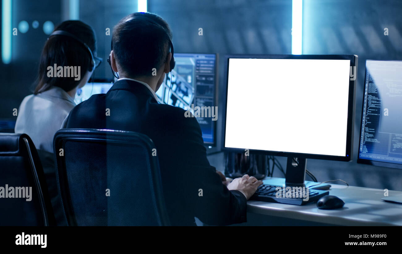 Government Agent is Working in Surveillance Control Center Full of Monitors and Servers. Possibly Government Agency Conducts Investigation. Stock Photo
