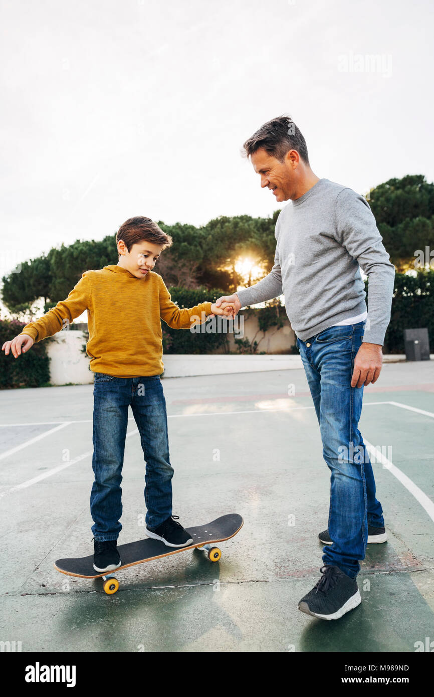 Father assisting son riding skateboard Stock Photo