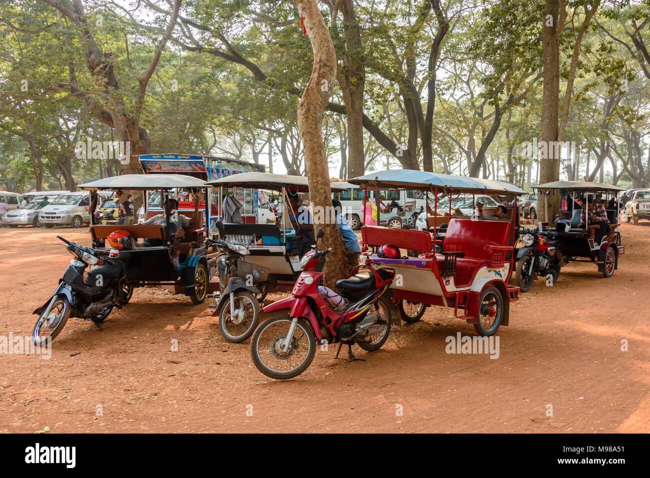 Drivers wait with their parked tuk-tuks (motorcycles with a trailer used as a taxi) in Cambodia. Stock Photo