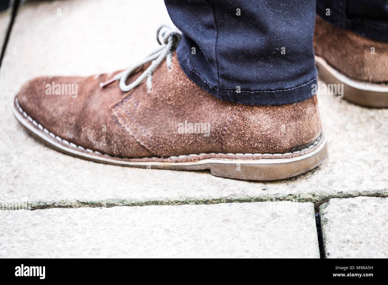 Mans brown suede loafer shoes on concrete slabs. Stock Photo