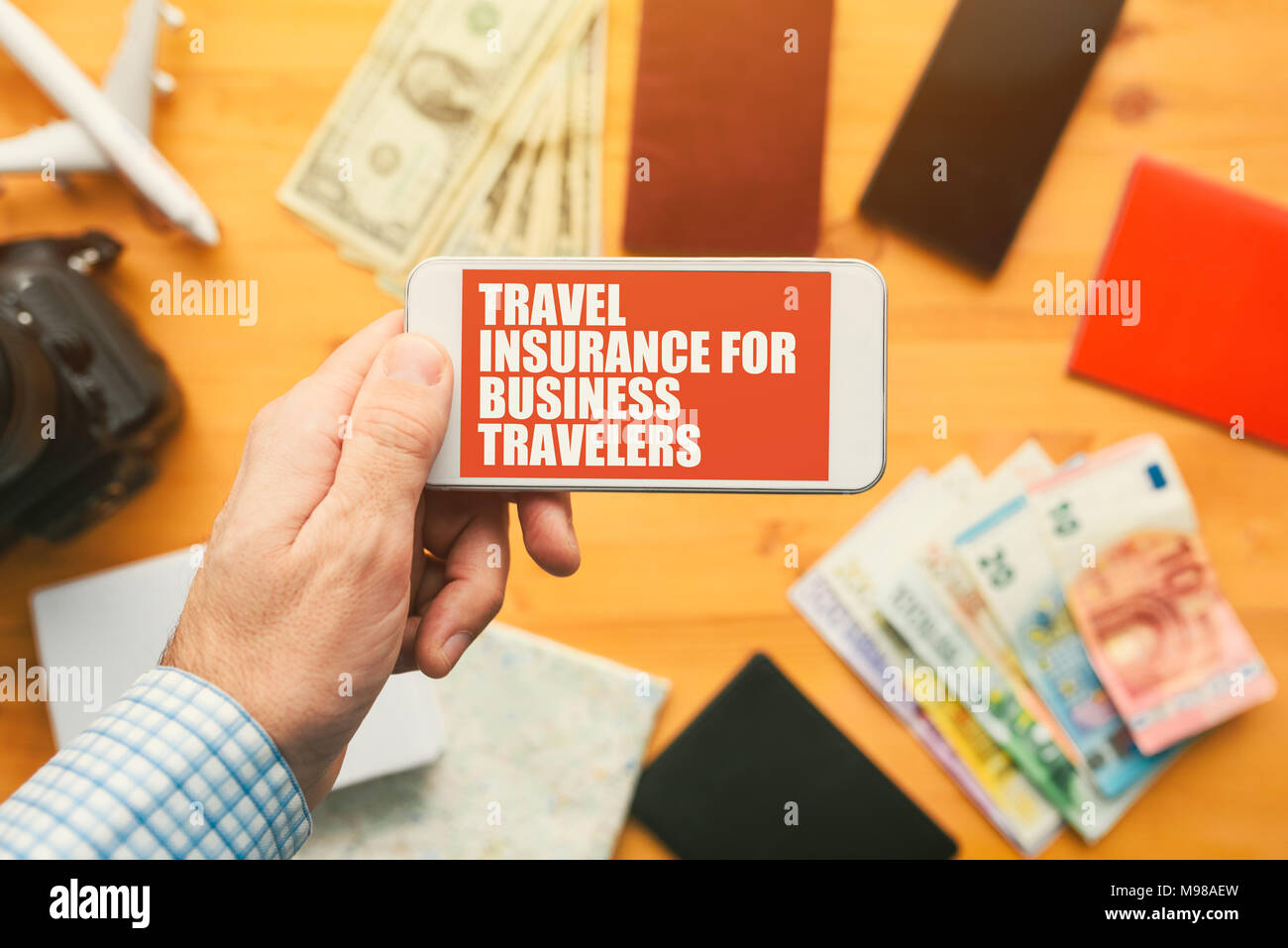 Travel insurance for business travelers online mobile phone app. Man holding smartphone with mock up application screen related to holiday vacation jo Stock Photo