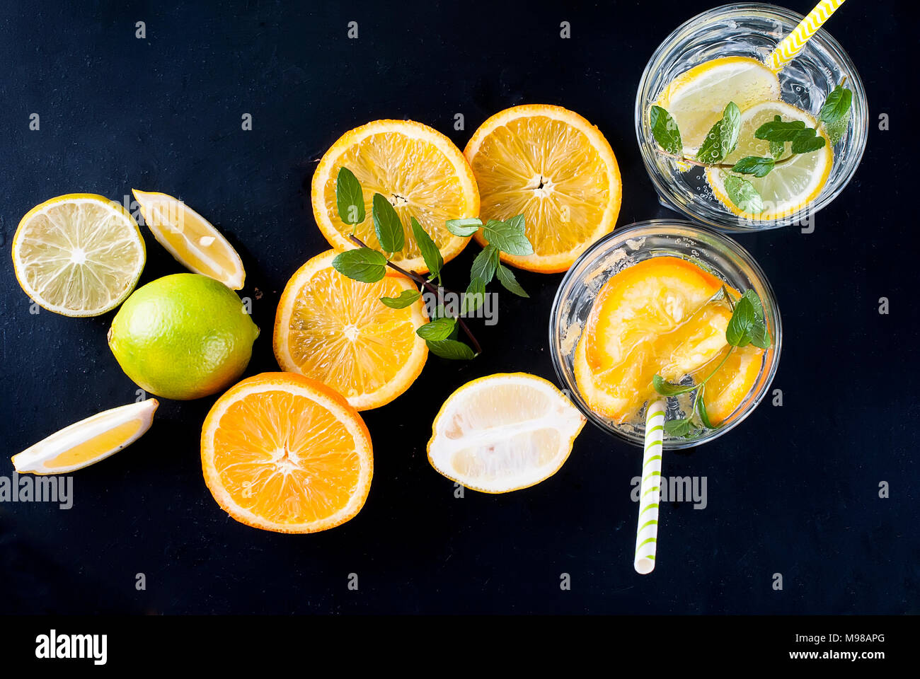 Fresh homemade lemonade in glass with lemon, orange, ice and mint. Ingredients for lemonade. Stock Photo