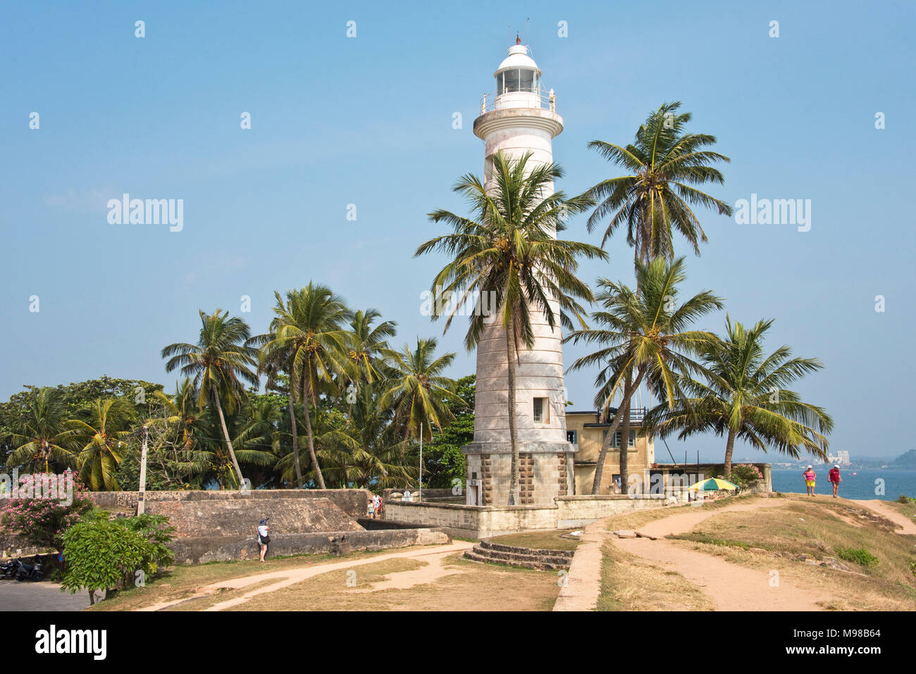Galle Lighthouse in Sri Lanka with tourists and local people walking around on a sunny day with blue sky. Stock Photo