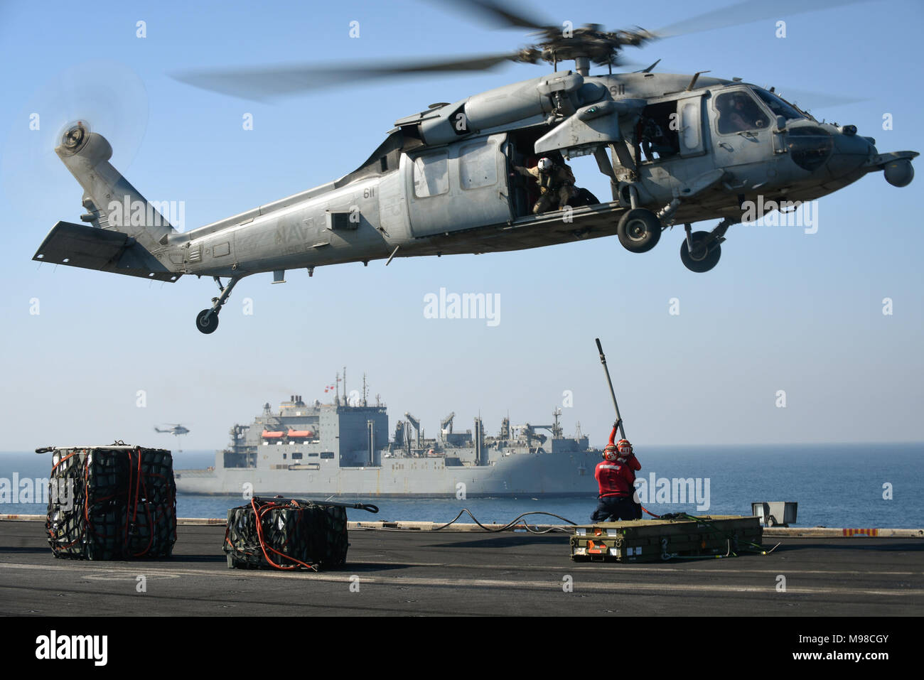 180320-N-NG033-1309  ARABIAN GULF (March 20, 2018) Aviation Ordnanceman 1st Class Jose Pando, left, and Aviation Ordnanceman Airman Margaret Torbeck attach ordnance to an MH-60S Sea Hawk helicopter assigned to the Indians of Helicopter Sea Combat Squadron (HSC) 6 on the flight deck of the aircraft carrier USS Theodore Roosevelt (CVN 71) during an ammunition offload with the dry cargo and ammunition ship USNS Amelia Earhart (T-AKE 6). Theodore Roosevelt and its carrier strike group are deployed to the U.S. 5th Fleet area of operations in support of maritime security operations to reassure allie Stock Photo