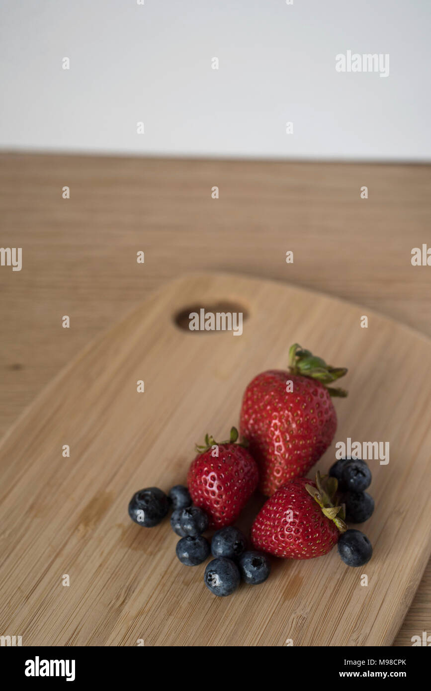 Blueberries and Strawberries on a Bamboo Cutting Board for a Healthy Snack or as Ingredient Preparation Stock Photo